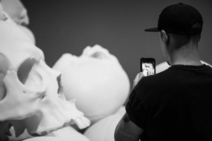 man photographing giant skull